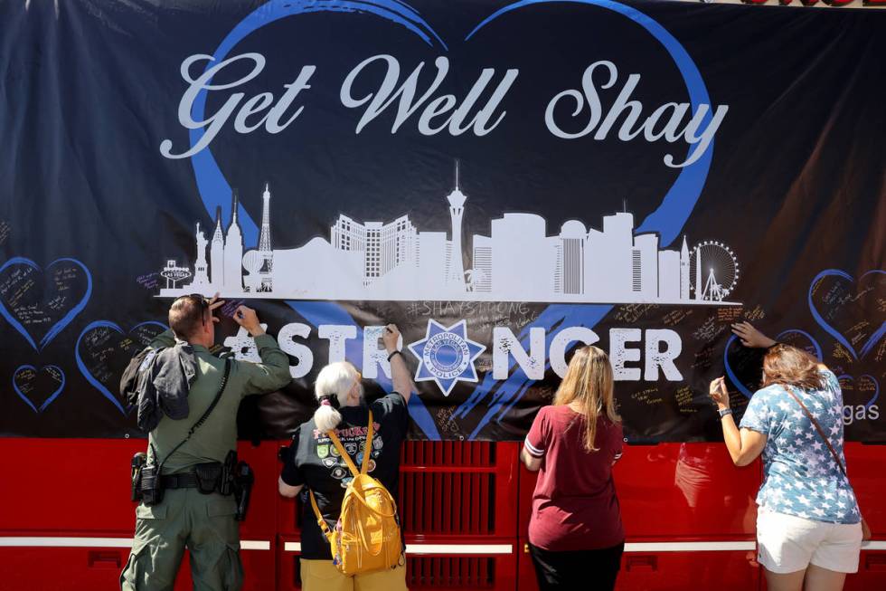 Las Vegas police officer Jim Bryant signs a banner with Pattie McBride, second from left, and S ...