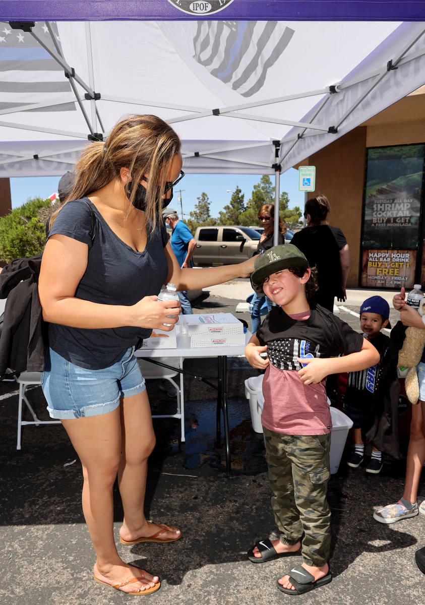 Darcy Barajas helps her son Blake, 8, try on a T-shirt during a fundraiser for Las Vegas police ...