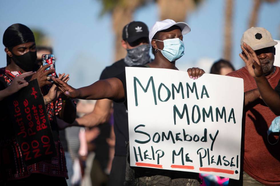 Mary Gibbs, center, participates in a touch-free prayer at a protest against police brutality o ...