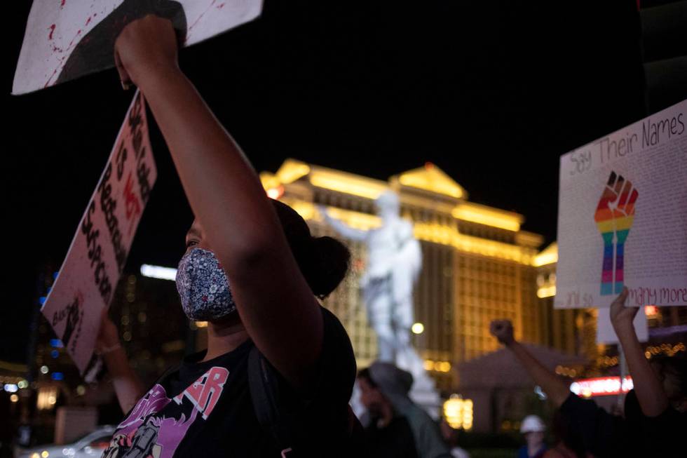 Protesters pause for street lights outside Caesars Palace during a protest against police bruta ...