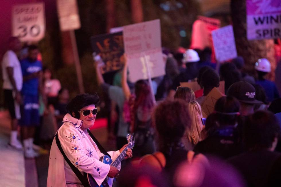 An Elvis impersonator interacts with protesters as they pass by during a protest against police ...