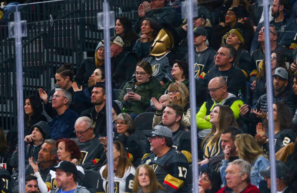 A Golden Knights fan wearing a mask watches the action during the first period of an NHL hockey ...