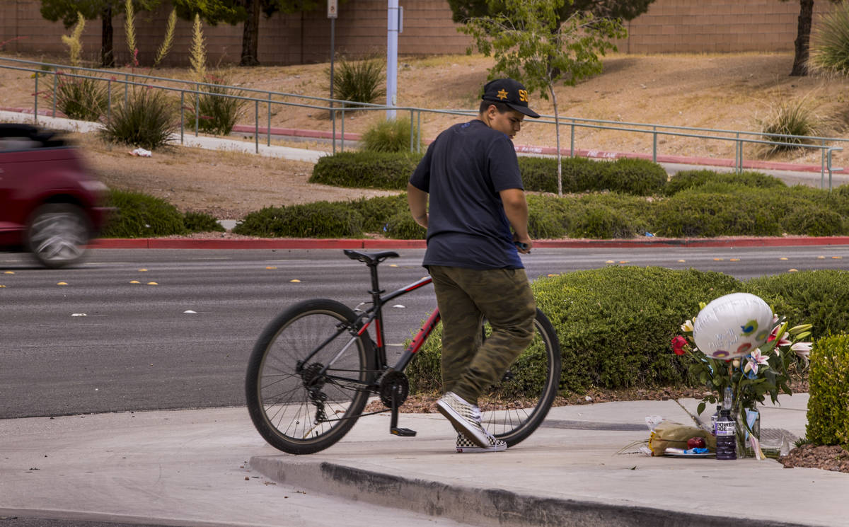 An unidentified cyclist walks by a small memorial near where two teen brothers were killed in a ...