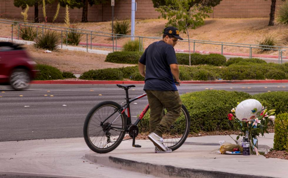 An unidentified cyclist walks by a small memorial near where two teen brothers were killed in a ...