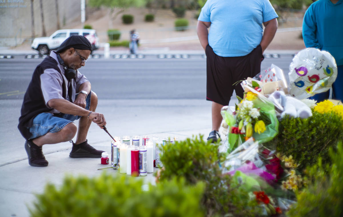 Mel E. lights candles as people gather for a vigil in memory of David Cox, 18, and Brandon Cox, ...