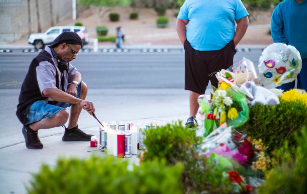 Mel E. lights candles as people gather for a vigil in memory of David Cox, 18, and Brandon Cox, ...