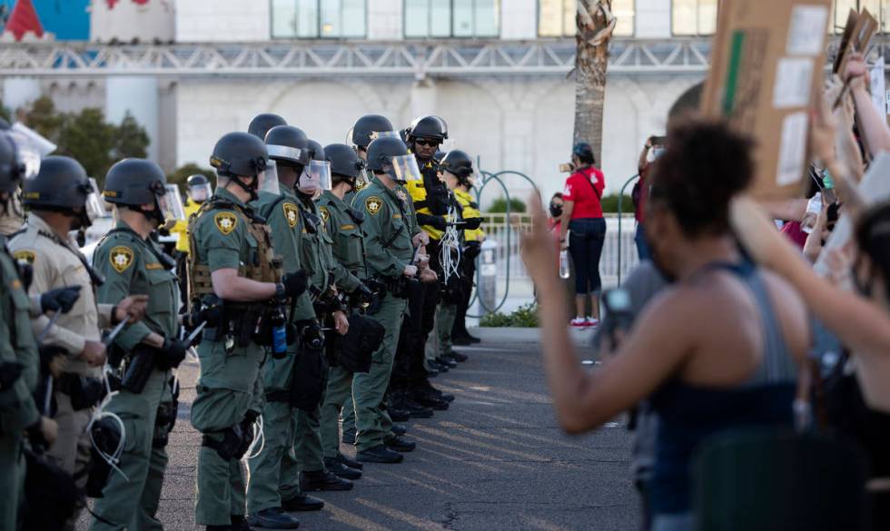 Police in riot gear and form a line outside Excalibur as protesters make way down Las Vegas Bou ...