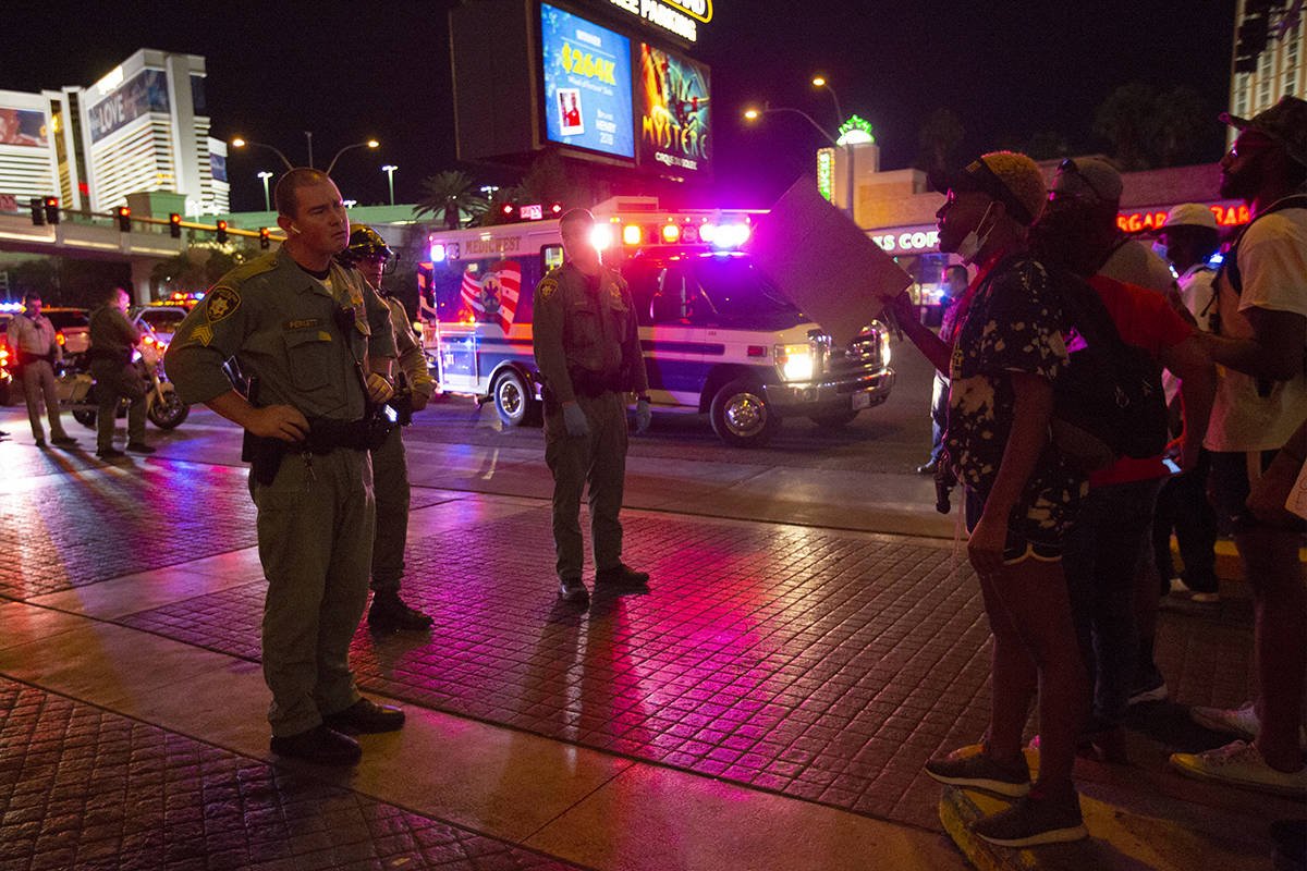 A protester argues with a Las Vegas Metropolitan Police officer as an ambulance arrives to take ...