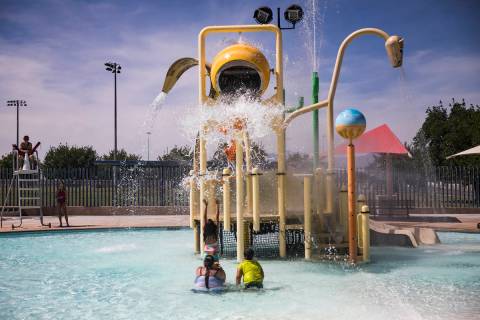 Swimmers await a bucket of water to fall from the water park at Garside Pool in Las Vegas, Mond ...