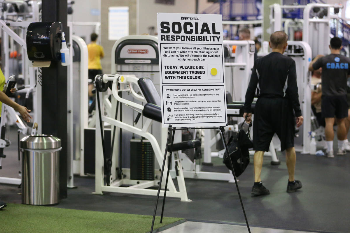 A sign reminds people of social distancing and sanitizing of equipment at the EOS Fitness gym i ...