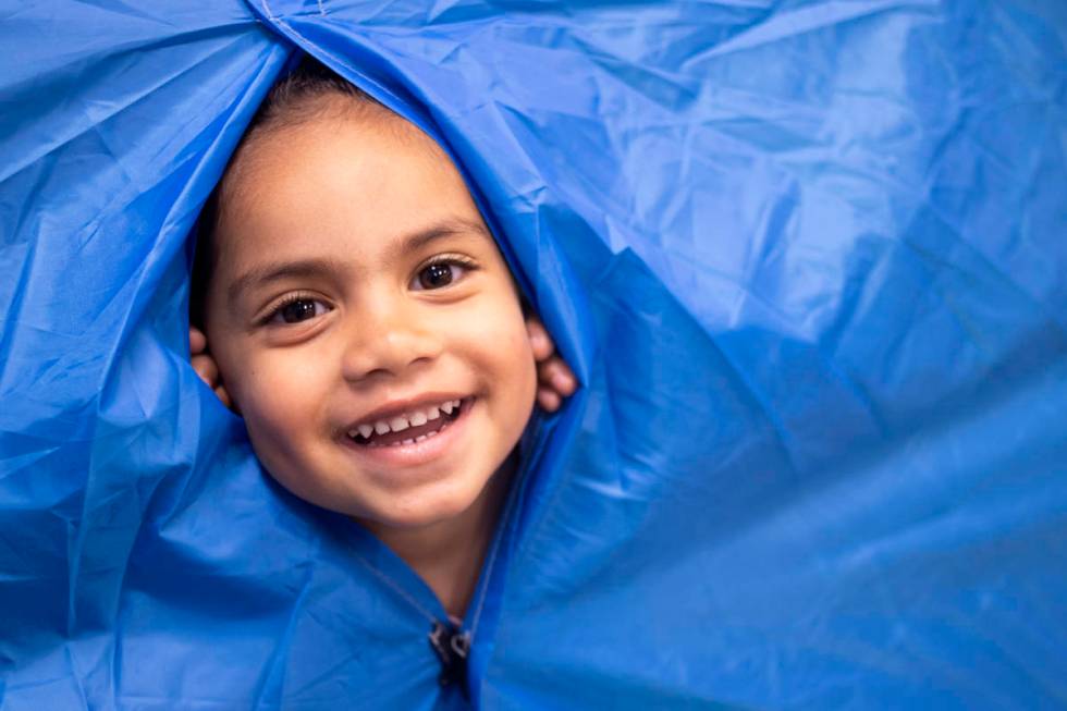 Paisley peeks through the tent, which is in one of the preschool rooms for "camping week,& ...