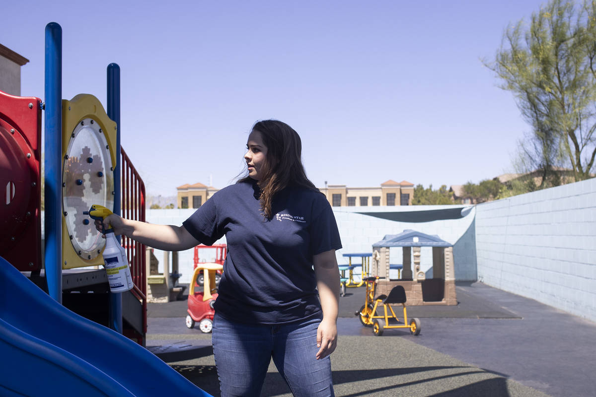 Miss Destaney sprays the playground with disinfectant after her class had outside time at Risin ...