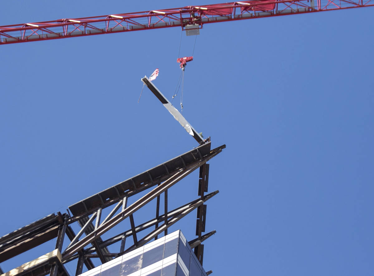 Workers hoist the last steel beam signed by Derek Stevens, CEO and developer of Circa Resort an ...