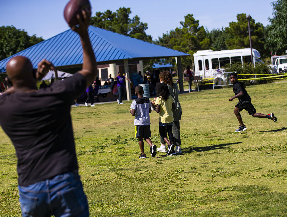 Charles Perry, left, throws a football to David Hicks, 11, during a Juneteenth event held by Sa ...