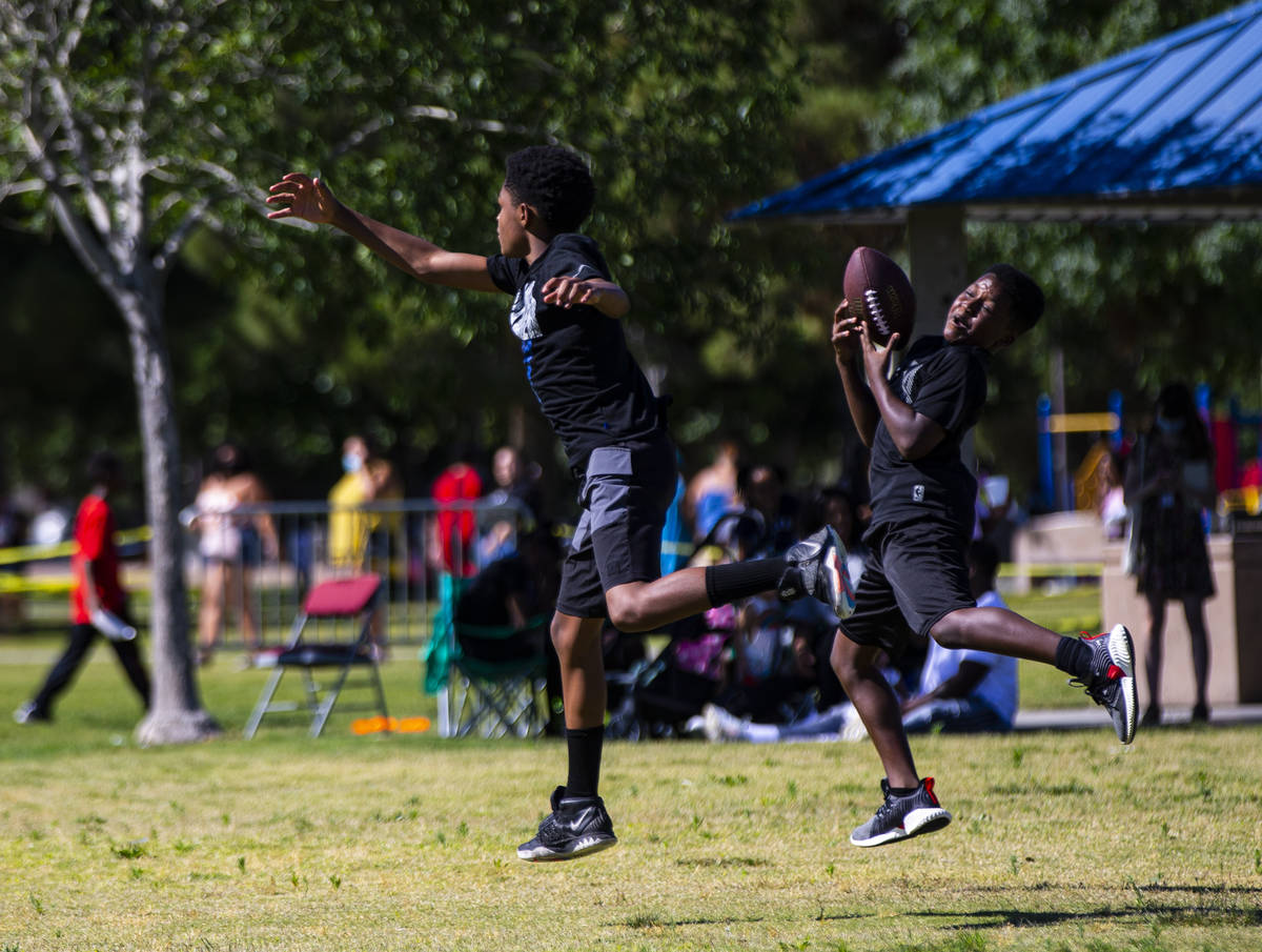 David Hicks, 11, right reaches for a football during a Juneteenth event held by Save Our Sons a ...