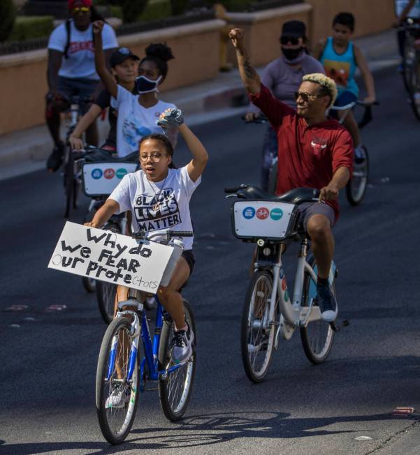 Participants in a Black Lives Matter bike ride against injustice show their support while passi ...