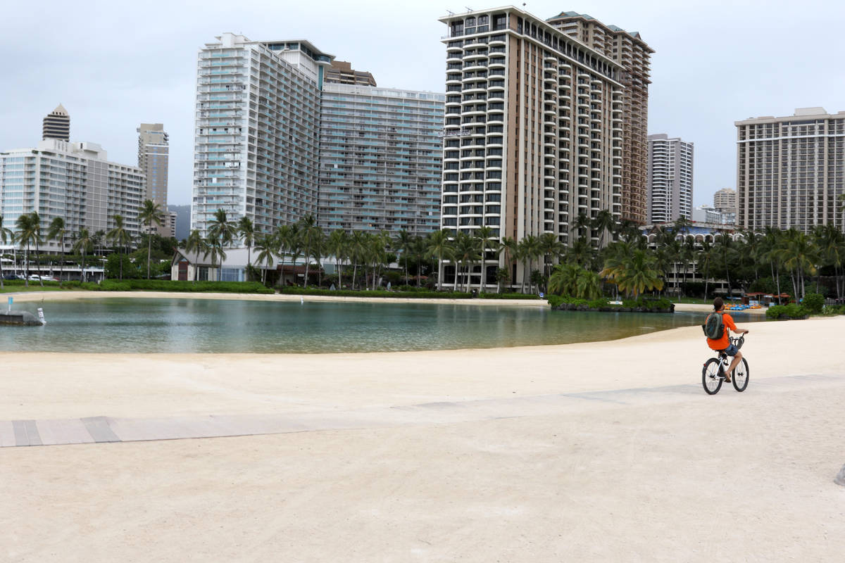 FILE - In this April 21, 2020, file photo, a man rides his bike on Waikiki Beach in Honolulu. F ...