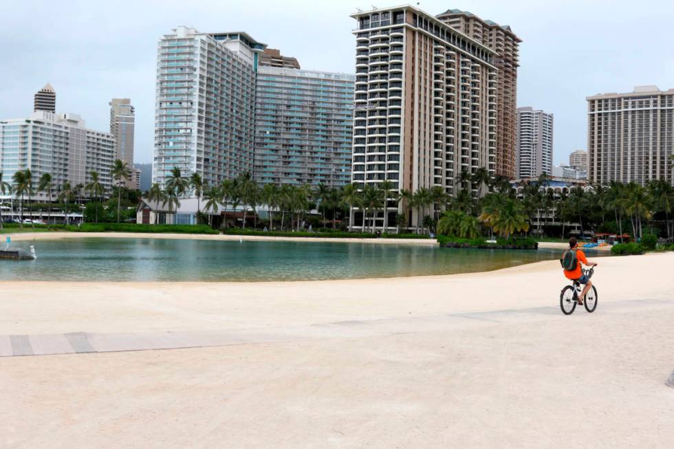 FILE - In this April 21, 2020, file photo, a man rides his bike on Waikiki Beach in Honolulu. F ...