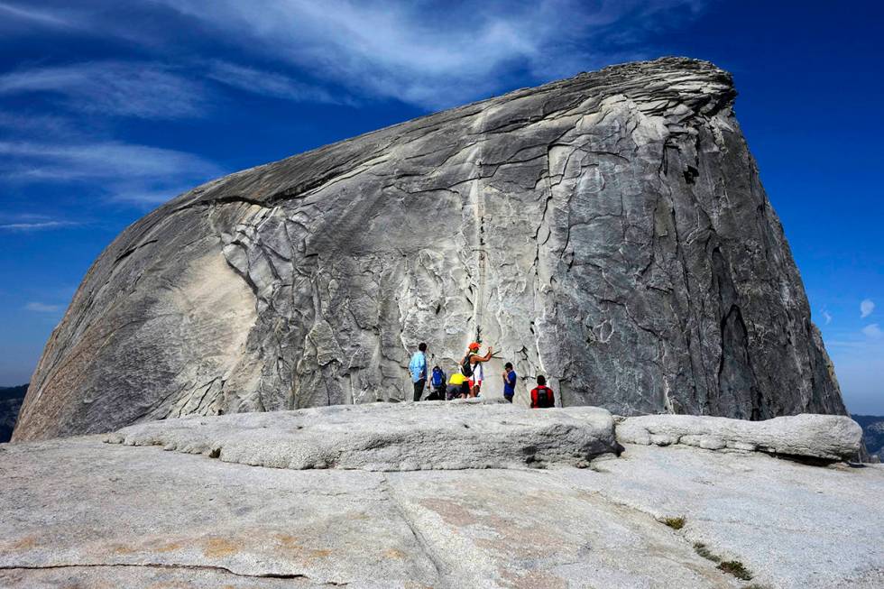 File - In this July 15, 2014, file photo, hikers gather in the foreground as climbers use the a ...