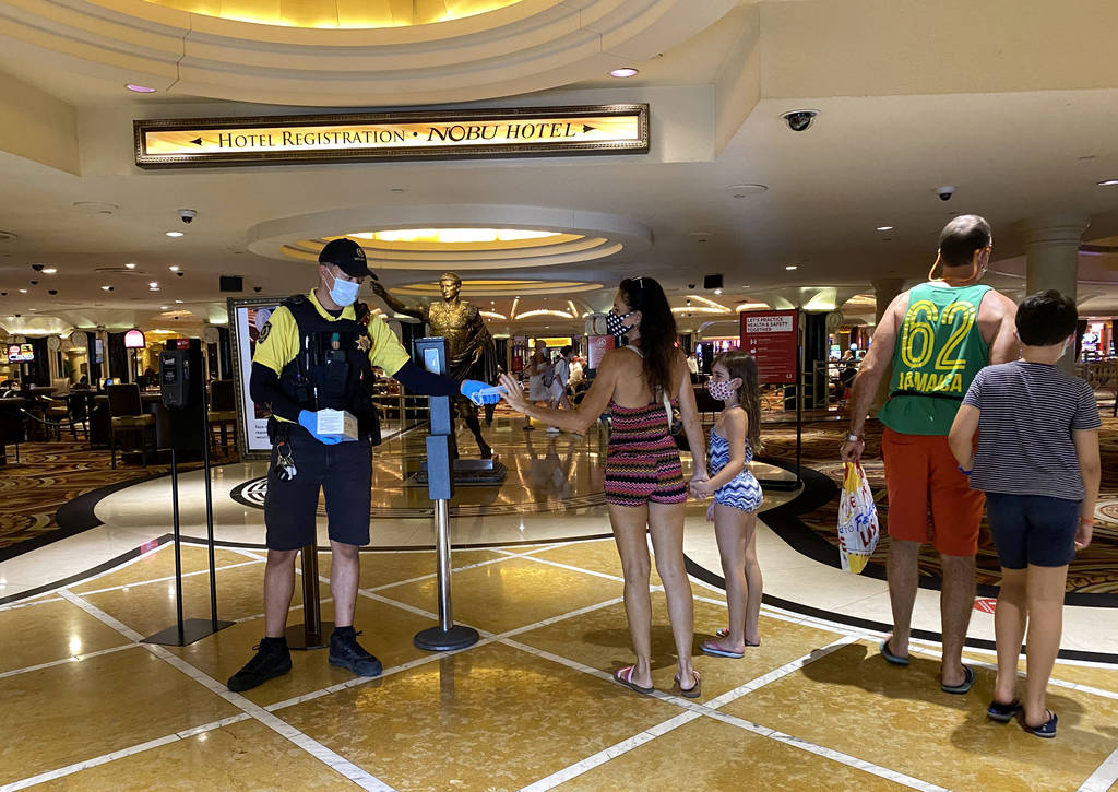 A security guard hands out face masks at Caesars on the Strip in Las Vegas Wednesday, June 24, ...