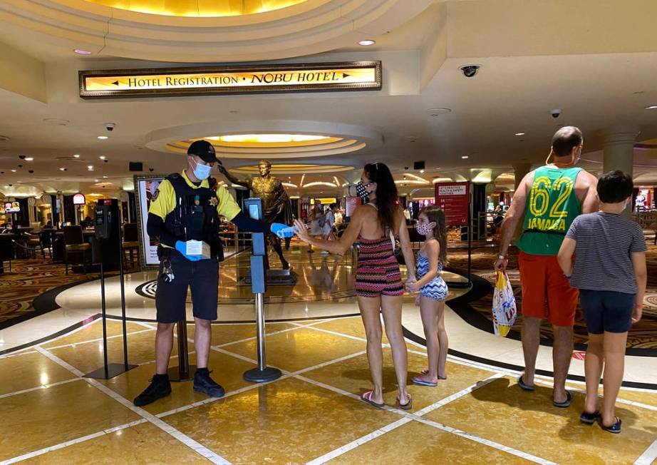 A security guard hands out face masks at Caesars on the Strip in Las Vegas Wednesday, June 24, ...