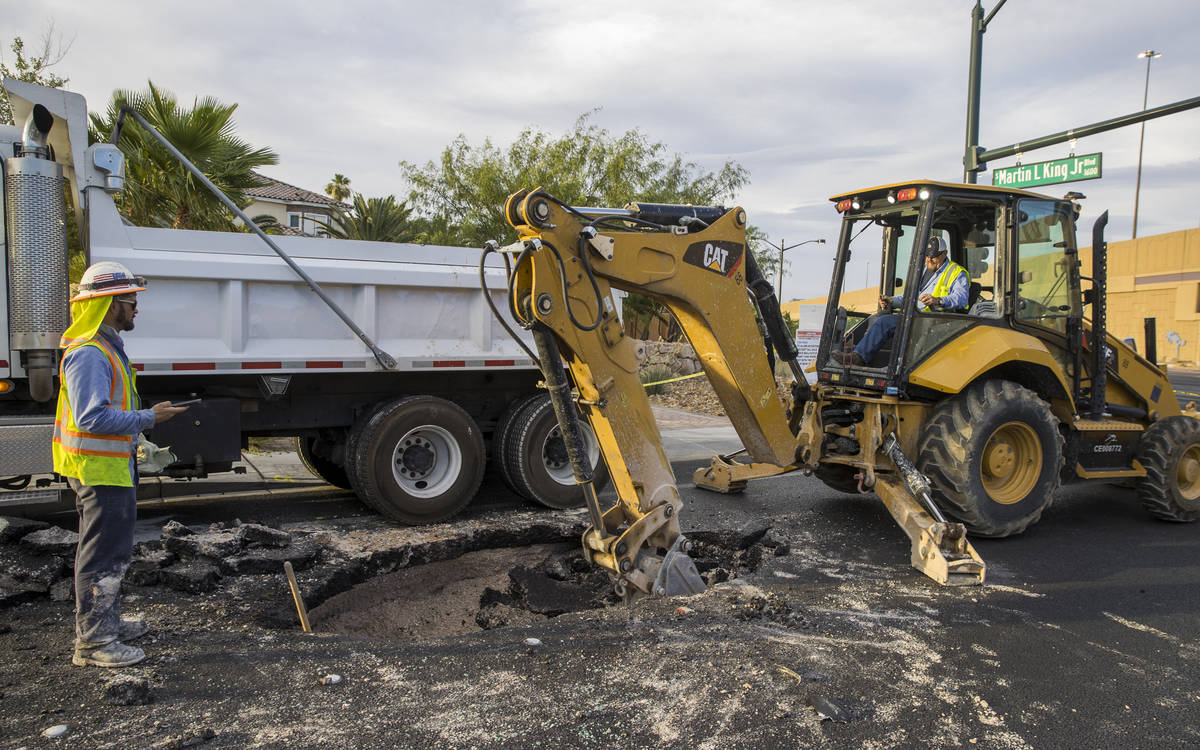 Las Vegas Valley Water District workers excavate a sinkhole which opened up and damaged vehicle ...
