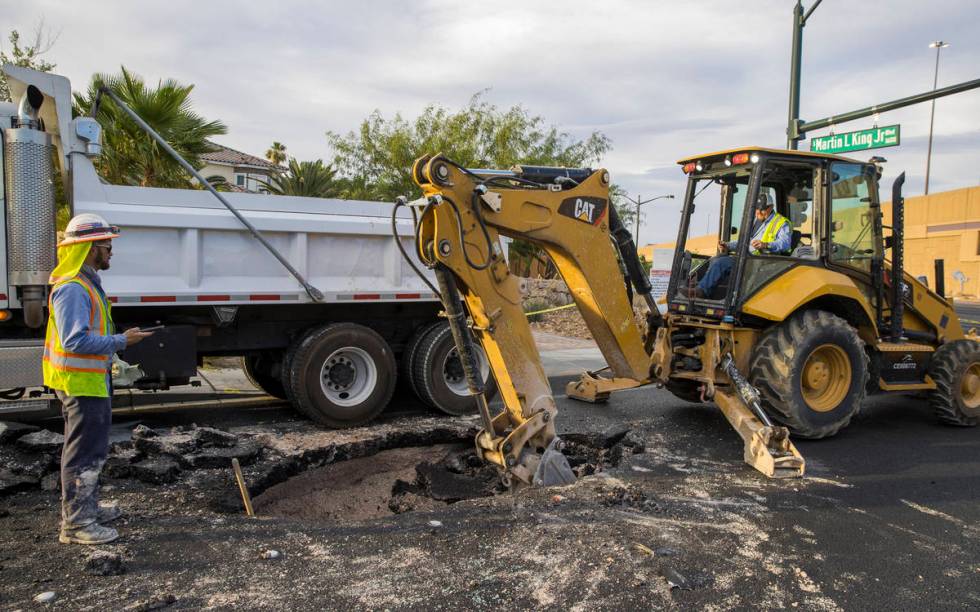 Las Vegas Valley Water District workers excavate a sinkhole which opened up and damaged vehicle ...