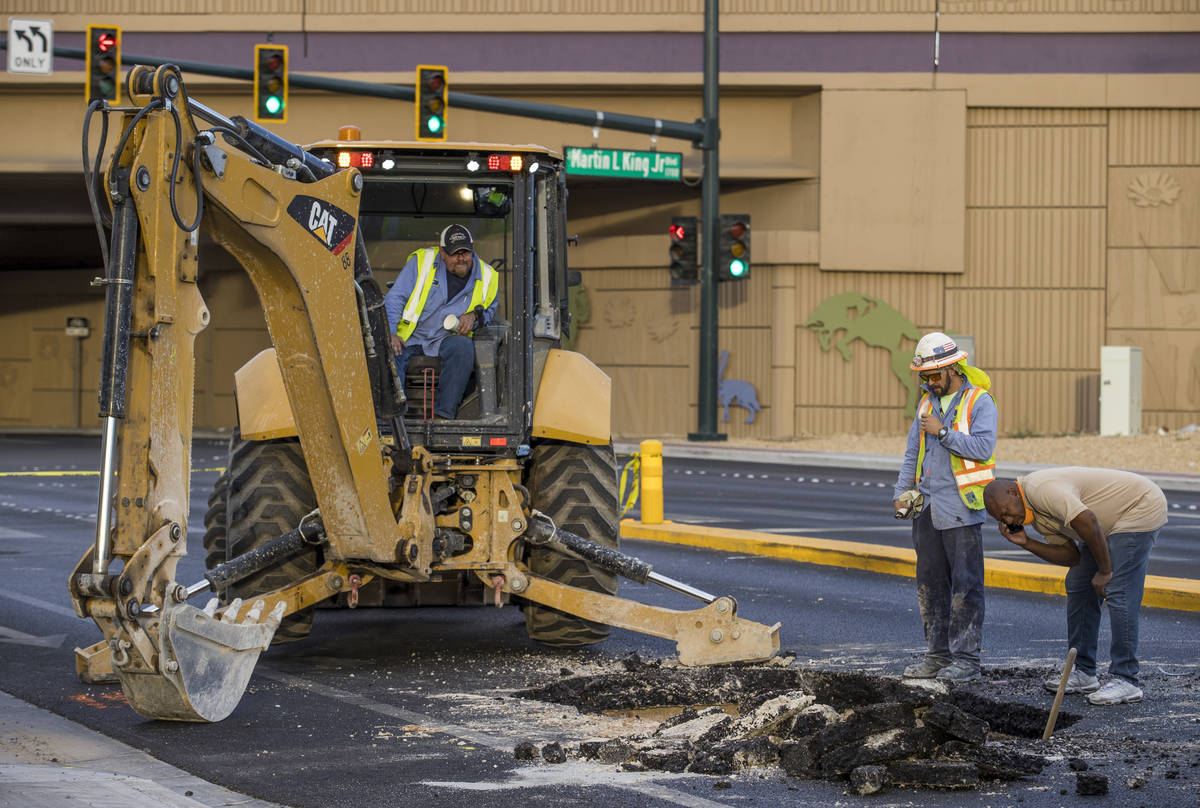 Las Vegas Valley Water District workers inspect a sinkhole which opened up and damaged vehicles ...