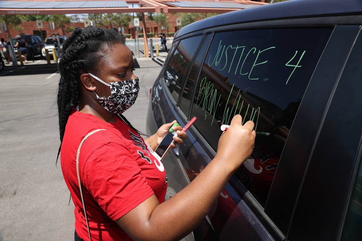 Tia Coward, event organizer and Las Vegas resident, writes a message on her car in advance of a ...