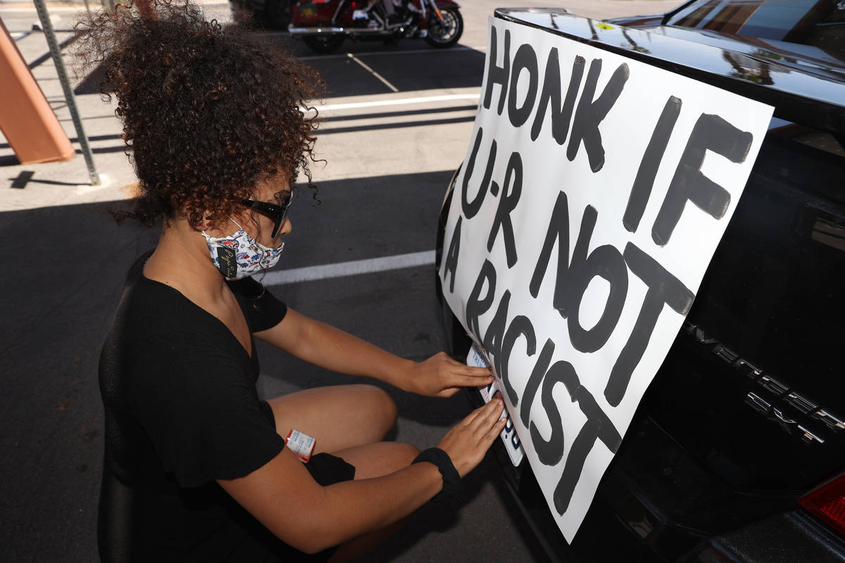 Nakita, a Las Vegas resident who declined to give a last name, hangs a banner to her car in adv ...