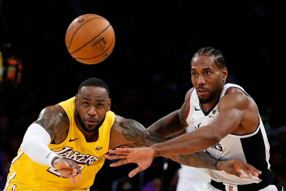 Los Angeles Lakers' LeBron James, left, and Los Angeles Clippers' Kawhi Leonard (2) chase the b ...