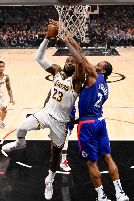 Los Angeles Lakers forward LeBron James, left, shoots as Los Angeles Clippers forward Kawhi Leo ...