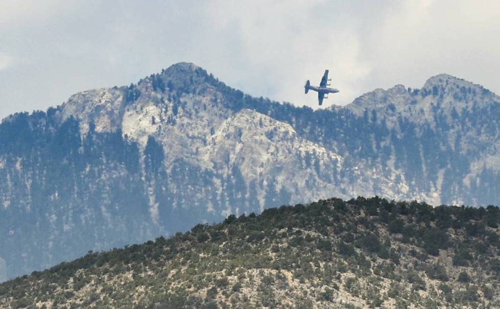 An air tanker circles after dropping fire retardant behind the ridge line while fighting the Ma ...