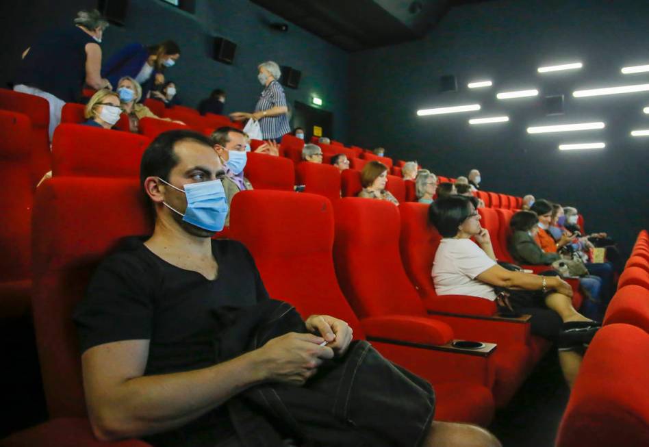 People wear protective masks as they wait for the screening of a movie in Paris, Monday, June 2 ...