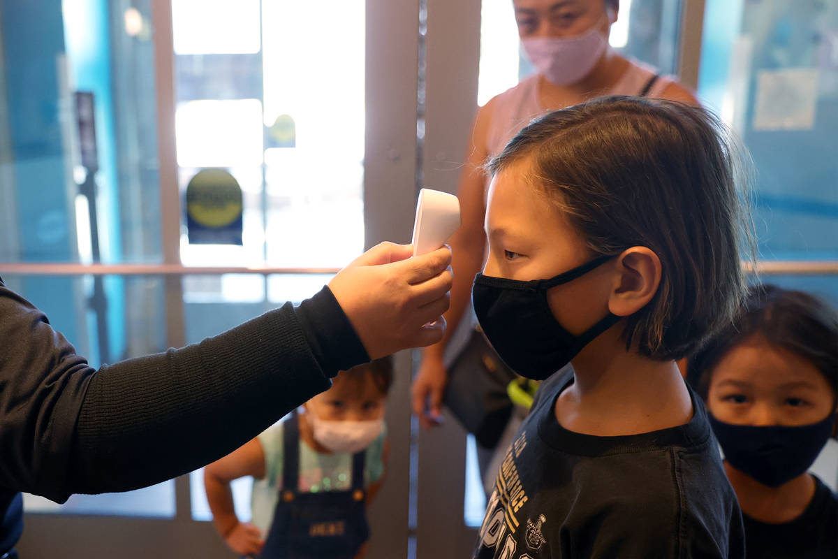 Kian Cram, 8, of Las Vegas, gets a temperature check as his family watches, from left, Emily, 3 ...