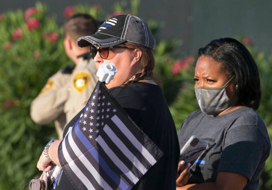 Cindy Novak, left, and Nakia Jackson-Hale watch a procession as an ambulance carrying a wounded ...