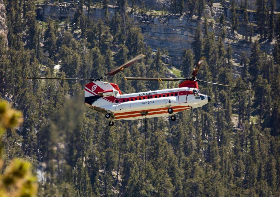 A helicopter with water bucket fills up at the Lee Canyon Ski Resort for another drop over the ...