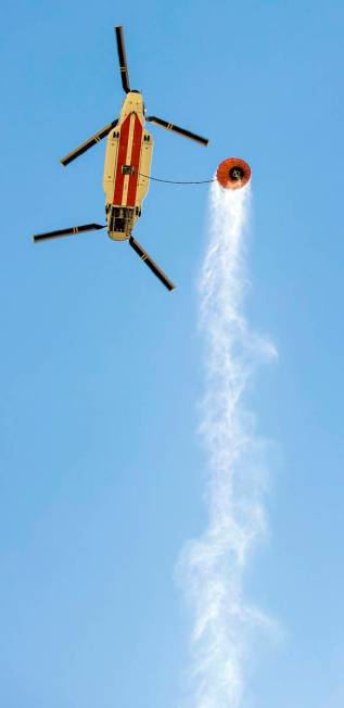 A helicopter with water bucket leaves the Lee Canyon Ski Resort for another drop over the Mahog ...