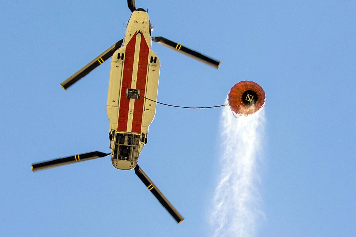 A helicopter with water bucket leaves the Lee Canyon Ski Resort for another drop over the Mahog ...