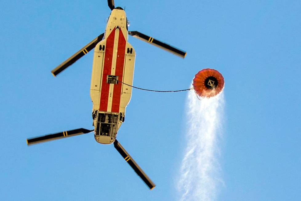 A helicopter with water bucket leaves the Lee Canyon Ski Resort for another drop over the Mahog ...