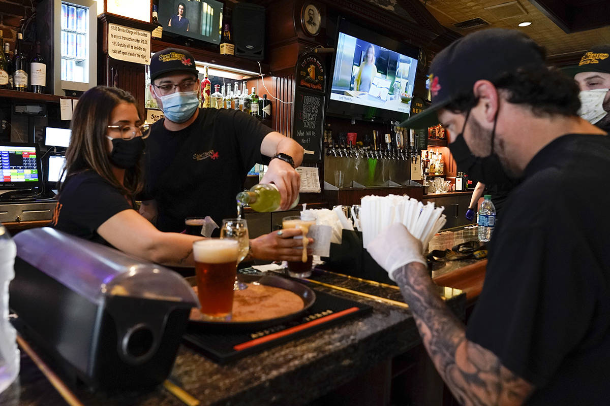 Jessica Ciaramitaro, Daryn Feenstra and Nicholas Soriano mix drinks while wearing face masks at ...