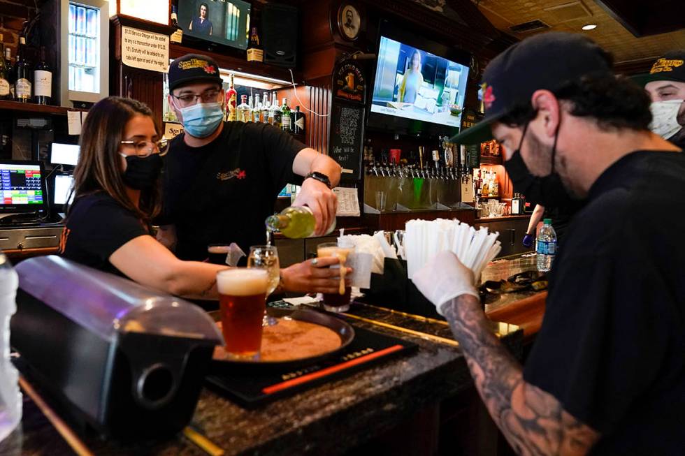 Jessica Ciaramitaro, Daryn Feenstra and Nicholas Soriano mix drinks while wearing face masks at ...