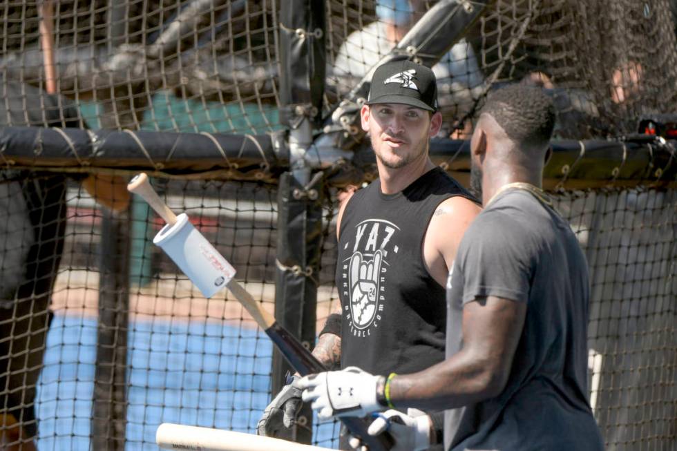 Chicago White Sox Yasmani Grandal, left, talks with teammate Luis Robert, right, during batting ...