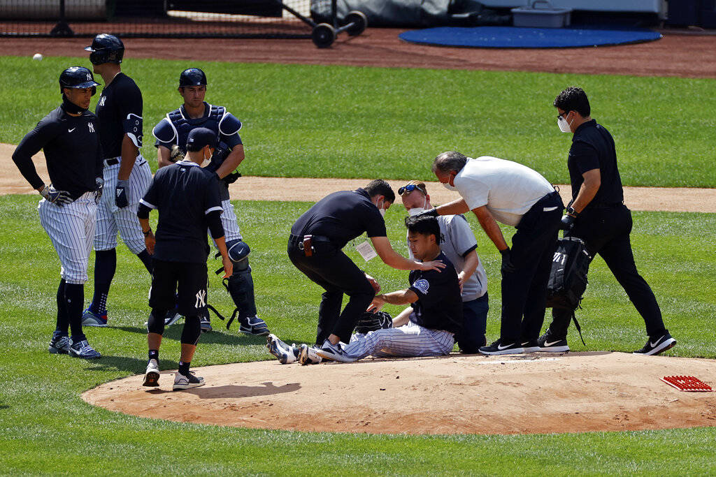 New York Yankees pitcher Masahiro Tanaka is tended to by team medical personnel after being hit ...