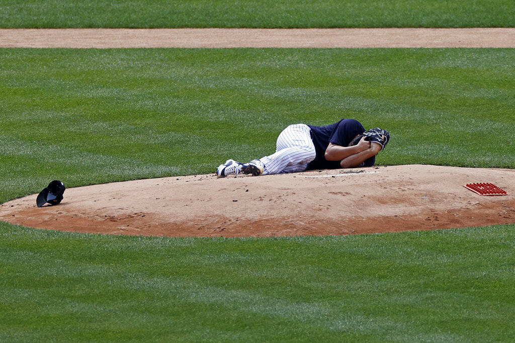 New York Yankees pitcher Masahiro Tanaka lies on the field after being hit by a ball off the ba ...