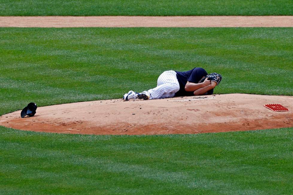 New York Yankees pitcher Masahiro Tanaka lies on the field after being hit by a ball off the ba ...