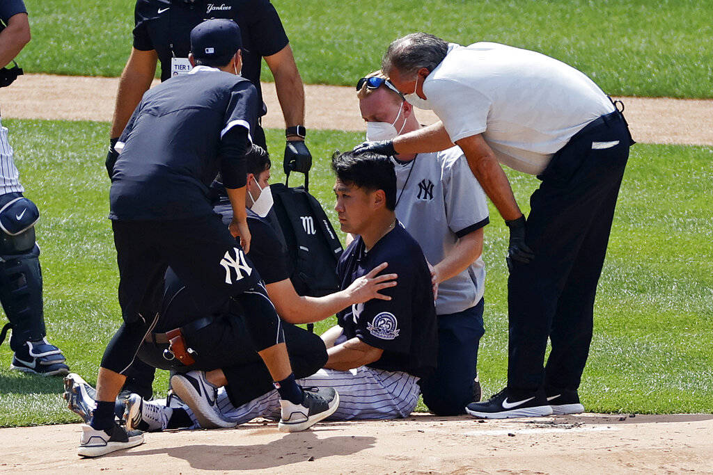 New York Yankees pitcher Masahiro Tanaka is tended to by team medical personnel after being hit ...