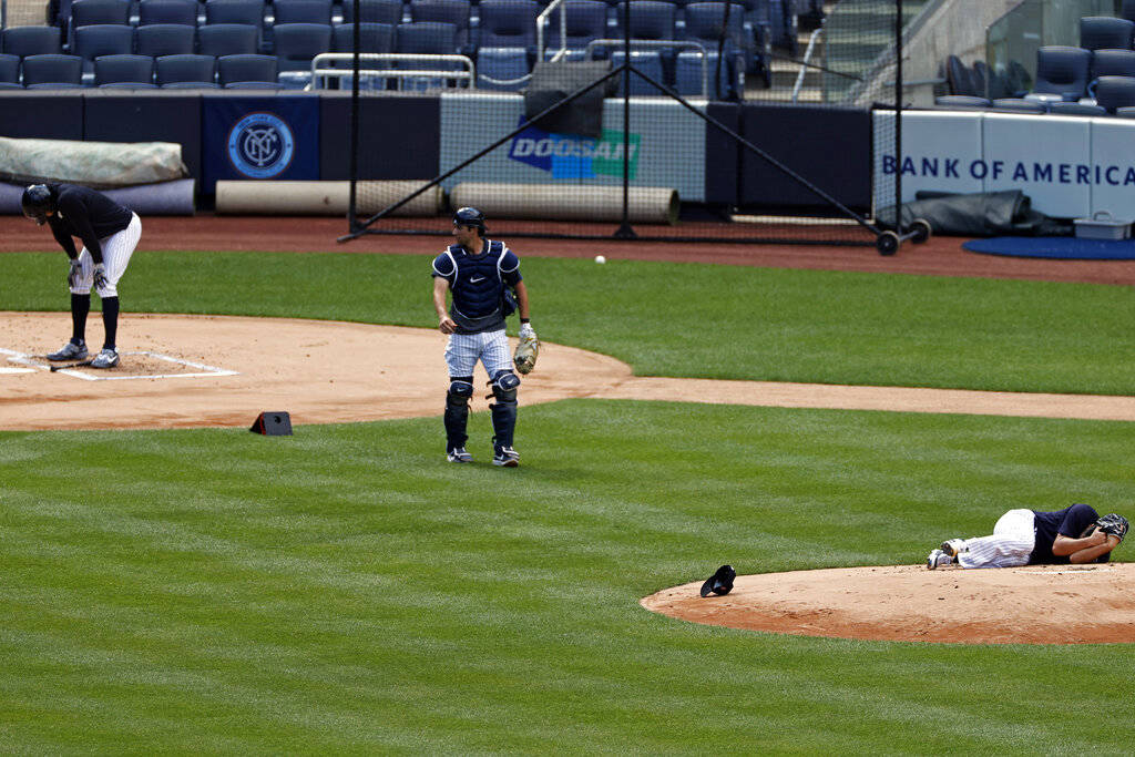 New York Yankees pitcher Masahiro Tanaka lies on the field after being hit by a ball off the ba ...