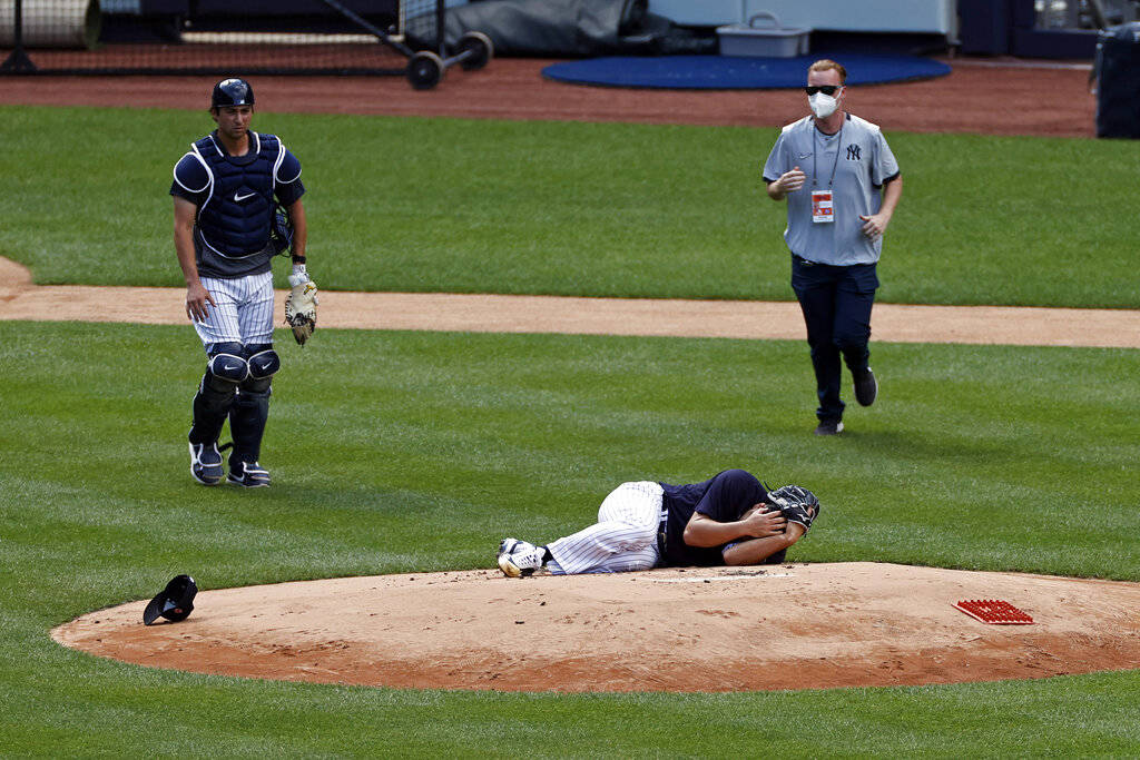 New York Yankees pitcher Masahiro Tanaka lies on the field after being hit by a ball off the ba ...