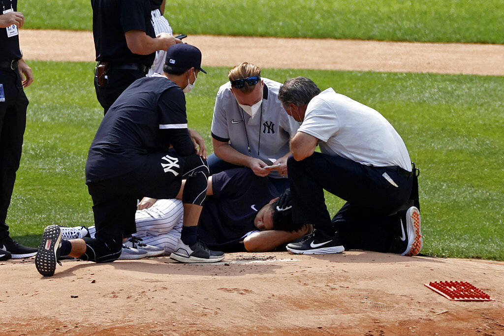 New York Yankees pitcher Masahiro Tanaka lies on the field after being hit by a ball off the ba ...